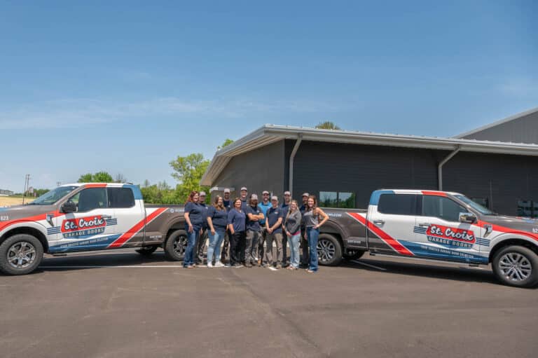 St. Croix Garage Doors team standing between branded service trucks outside company building